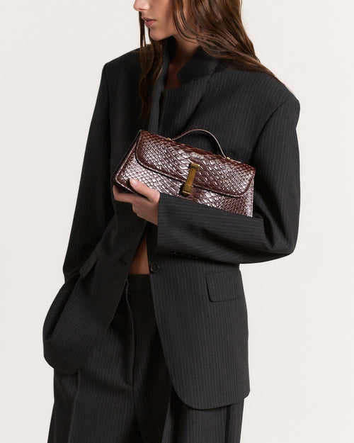 Kassandre Colonne clutch in brown python-effect leather with gold hardware, worn view