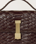 Kassandre Colonne clutch in brown python-effect leather with gold hardware, three quarter view