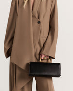 Kassandre Deva clutch in black cow leather with gold hardware, Art Deco geometry,removable strap , crossbody bag , worn view