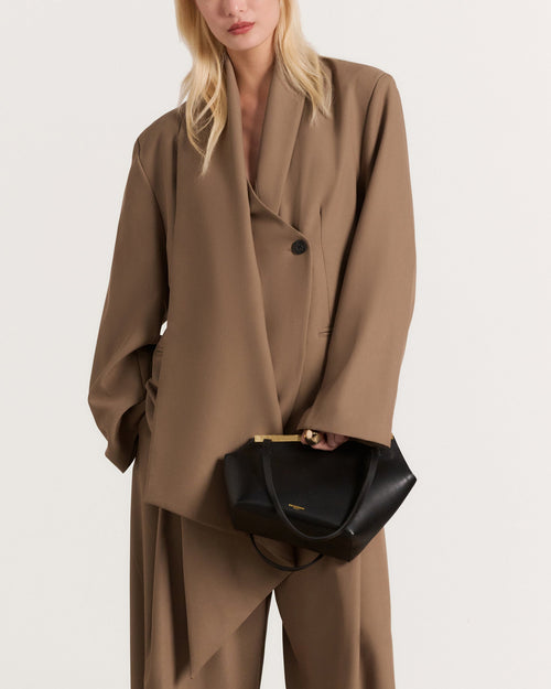 Kassandre Eileen asymmetric shoulder bag in black cow leather, architectural line, gold frame,worn view