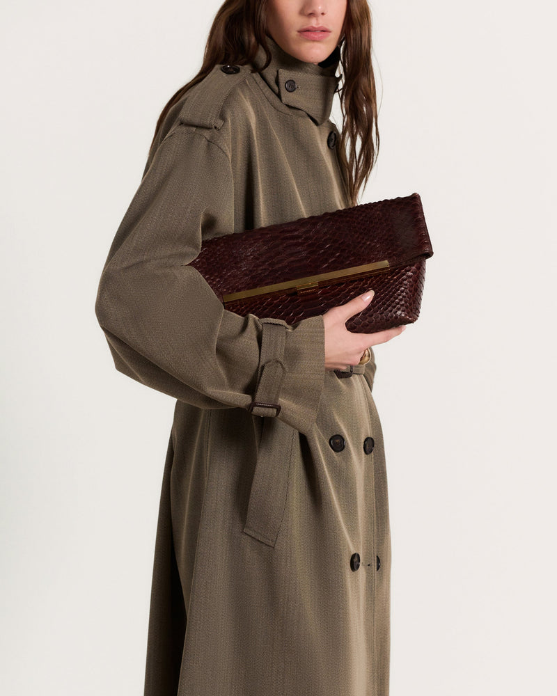 Kassandre Eileen clutch in brown python-effect leather with striped metal frame, worn view