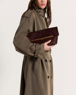 Kassandre Eileen clutch in brown python-effect leather with striped metal frame, worn view