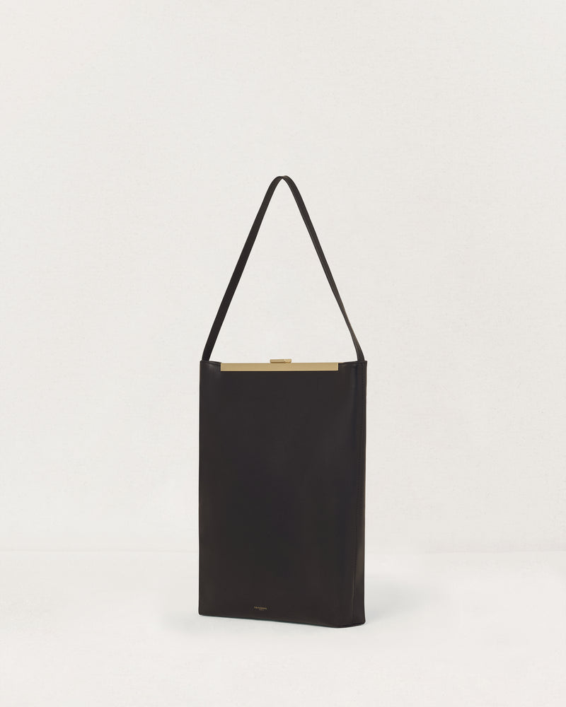 Kassandre Eileen computer bag in black cow leather with gold striped metal frame, three quarter view