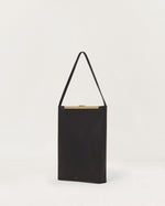 Kassandre Eileen computer bag in black cow leather with gold striped metal frame, three quarter view