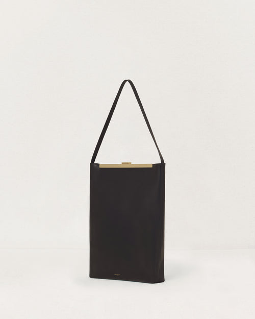 Kassandre Eileen computer bag in black cow leather with gold striped metal frame, three quarter view
