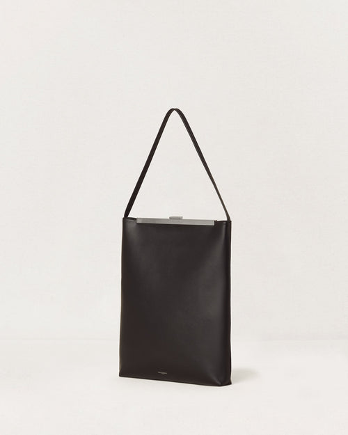 Kassandre Eileen computer bag in black cow leather with silver striped metal frame,three quarter view
