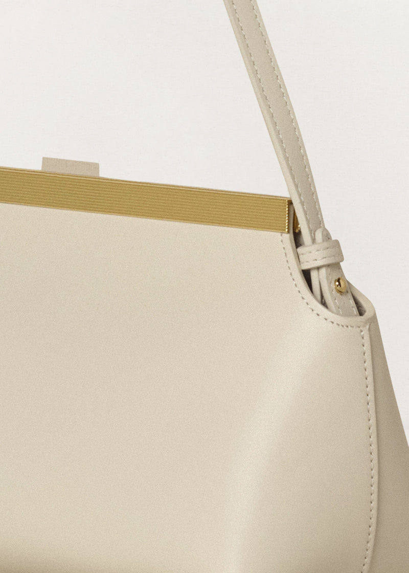 Kassandre Eileen shoulder bag in off-white cow leather with gold striped metal frame, detail handle view