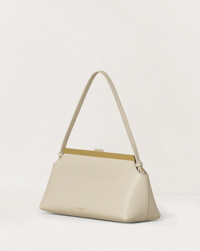 Kassandre Eileen shoulder bag in off-white cow leather with gold striped metal frame, three quarter view