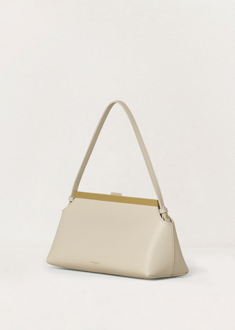 Kassandre Eileen shoulder bag in off-white cow leather with gold striped metal frame, three quarter view